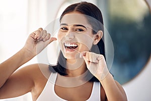 Smile, woman in bathroom flossing teeth and morning dental care routine in home mirror. Health, wellness and Indian