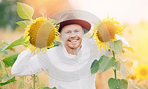 Smile young farmer man in hat in sunflowers field. Sunlight concept lifestyle summer happy