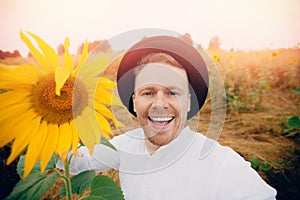 Smile young farmer man in hat in sunflowers field. Sunlight concept lifestyle summer happy