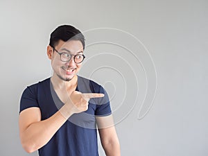 Smileing Asian man point on empty space.