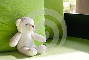 Smilely white teddy bear sit on sofa