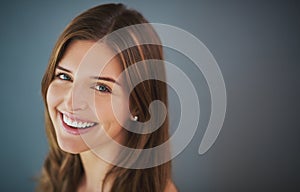 Smiles of certainty. Studio portrait of an attractive young woman posing against a gray background.