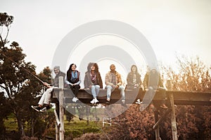 Smiles fade, but memories last a lifetime. a group of friends sitting on a pier together on a weekend breakaway.