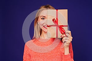 Smiley blond woman hiding face with gift box