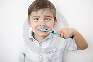 Smiley boy cleans a teeth isolated on grey background