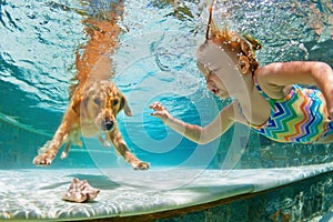 Smiley child with dog in swimming pool. Funny portrait.