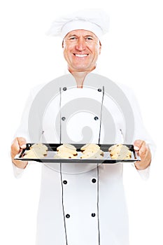 Smiley cook holding baking tray with cookies