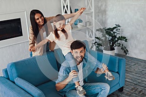 Smiley dad playing with his wife and kid on couch