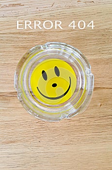 smiley face on an ashtray on wood background with text