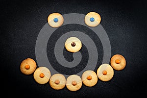 Smiley face of childish cookies on black background