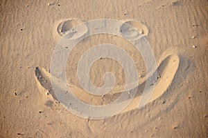 A smiley face drawing on a sand