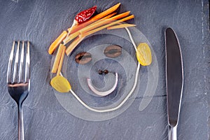 Smiley face made from vegetables, knife and fork