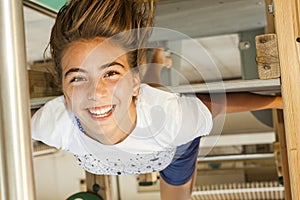 Smiley girl with long hair upsidedown in a swing at the park in