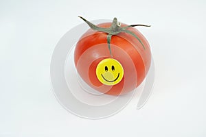 Smiley happy face on fresh organic red tomato isolated on white background