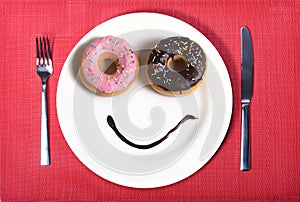 Smiley happy face made on dish with donuts eyes and chocolate syrup as smile in sugar and sweet addiction nutrition