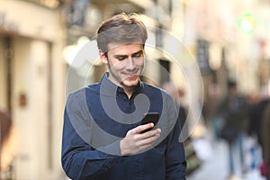 Smiley man checking smart phone content in the street