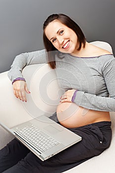 Smiley pregnant woman with laptop