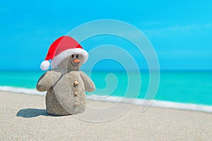 Smiley sandy Snowman in red Santa hat at sea beach