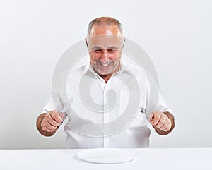 Smiley senior man holding fork with knife