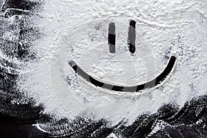 Smiley on white wheat flour at abstract black background