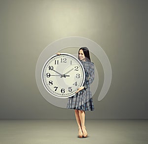 Smiley woman looking at big white clock