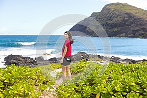 Smilig teen girl looking over shoulder, standing by rocky beach