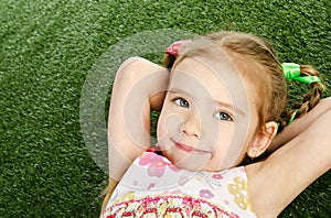 Smililing little girl lying on grass