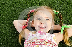 Smililing little girl lying on grass