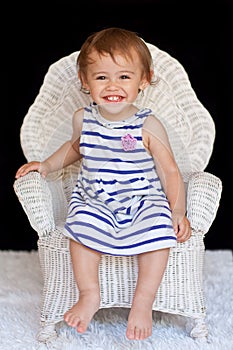 Smiling 1 year old multicultural girl in chair