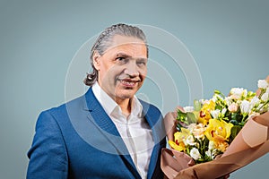 Smiling 50 year old man in suit with bouquet of flowers