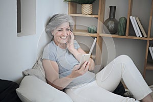Smiling 60s older senior middle-aged adult lady enjoying mobile for video conference calling virtual family