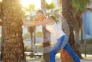 Smiling active woman stretching leg muscles outside