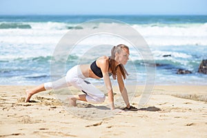 Smiling active young woman doing sports excercises on the beach