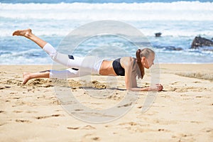 Smiling active young woman doing sports excercises on the beach