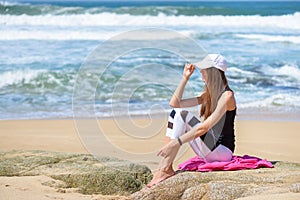 Smiling active young woman in sports outfit on the beach