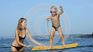 Smiling adorable child enjoying blue sea surfboarding bodyboard. Slow motion