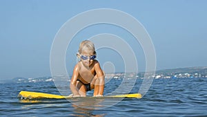 Smiling adorable child enjoying blue sea surfboarding bodyboard. Slow motion