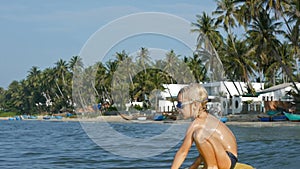 Smiling adorable child enjoying blue sea surfboarding bodyboard. Slow motion