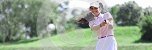 Smiling adult caucasian woman in golf club hitting on ball portrait.