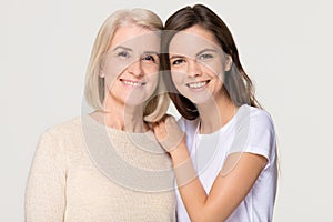 Smiling adult daughter and old mother bonding isolated on background