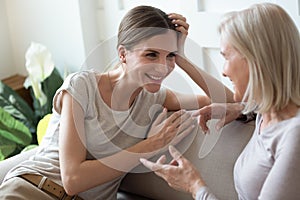 Smiling adult daughter talking with older mother at home