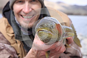 Happy fisherman holding large trout