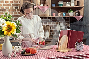 smiling adult housewife cutting bell pepper