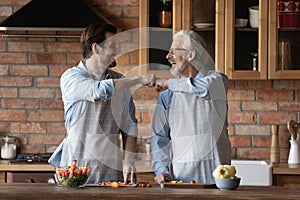 Smiling adult son and old dad cooking food