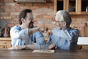 Smiling adult son and old dad play board game