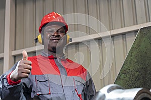 Smiling African American Blue-Collar Worker Giving Thumbs Up In A Factory