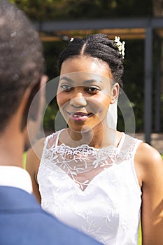 Smiling african american bride with groom at wedding ceremony in sunny garden