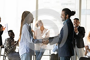 Smiling African American business partners shaking hands at meeting