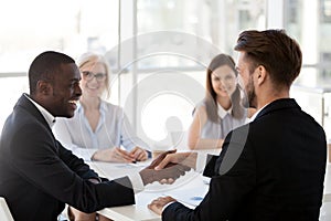 Smiling African American businessman shake hand of colleague at briefing