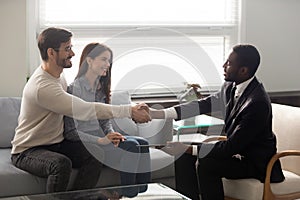 Smiling african american businessman in suit shaking hands with man.
